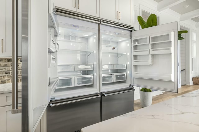 kitchen featuring white cabinetry, built in fridge, and light stone counters