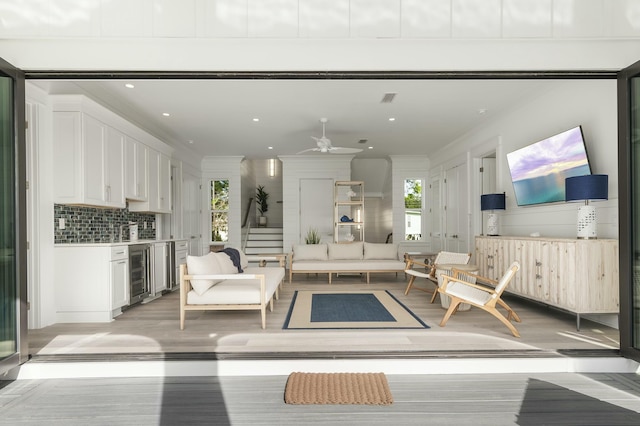 living room with wine cooler, ornamental molding, light hardwood / wood-style floors, and ceiling fan