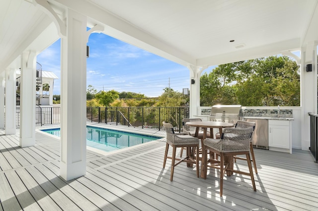 wooden deck with area for grilling and a fenced in pool