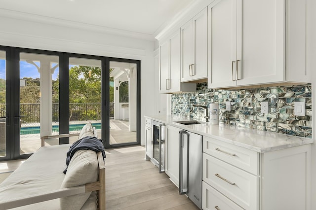 kitchen with light stone countertops, white cabinets, backsplash, and light hardwood / wood-style flooring