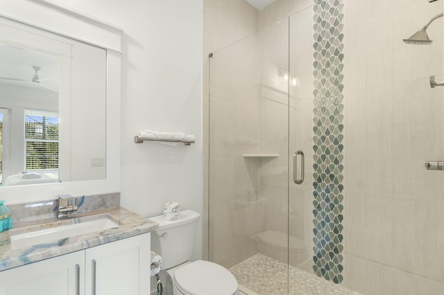 bathroom featuring toilet, vanity, ceiling fan, and walk in shower