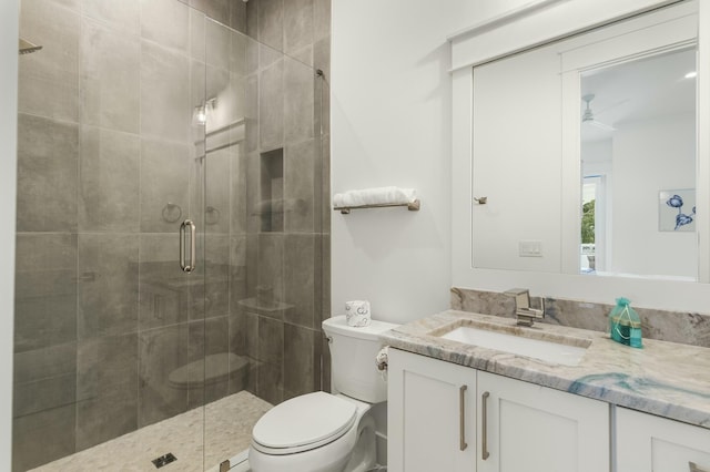 bathroom featuring vanity, an enclosed shower, toilet, and ceiling fan