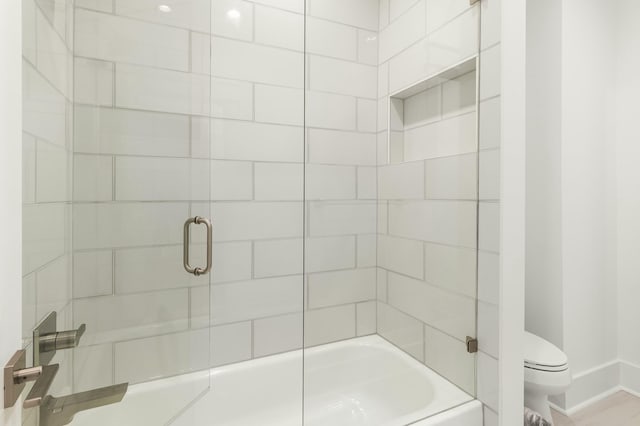 bathroom with bath / shower combo with glass door and toilet