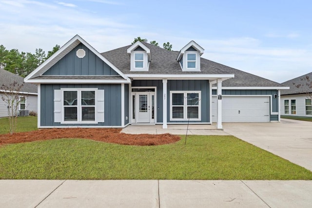 view of front facade with a garage, a porch, a front yard, and cooling unit