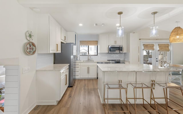 kitchen with white cabinetry, stainless steel appliances, light stone counters, and decorative light fixtures