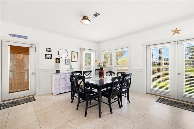 54 Rue Du Soleil, Santa Rosa Beach, FL 32459 - dining room featuring light tile patterned floors, a wainscoted wall, healthy amount of natural light, ornamental molding, and a decorative wall