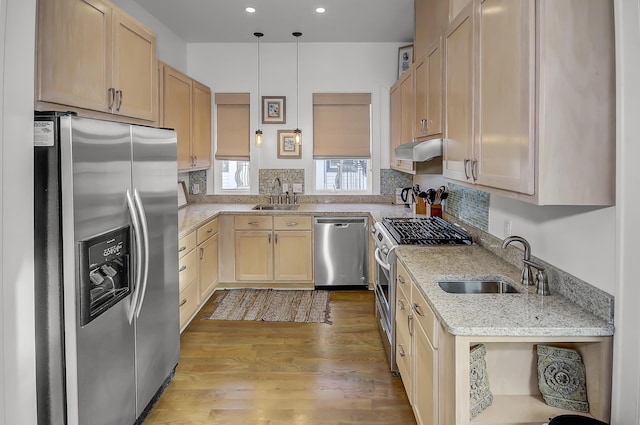 kitchen with appliances with stainless steel finishes, a sink, light stone counters, and under cabinet range hood