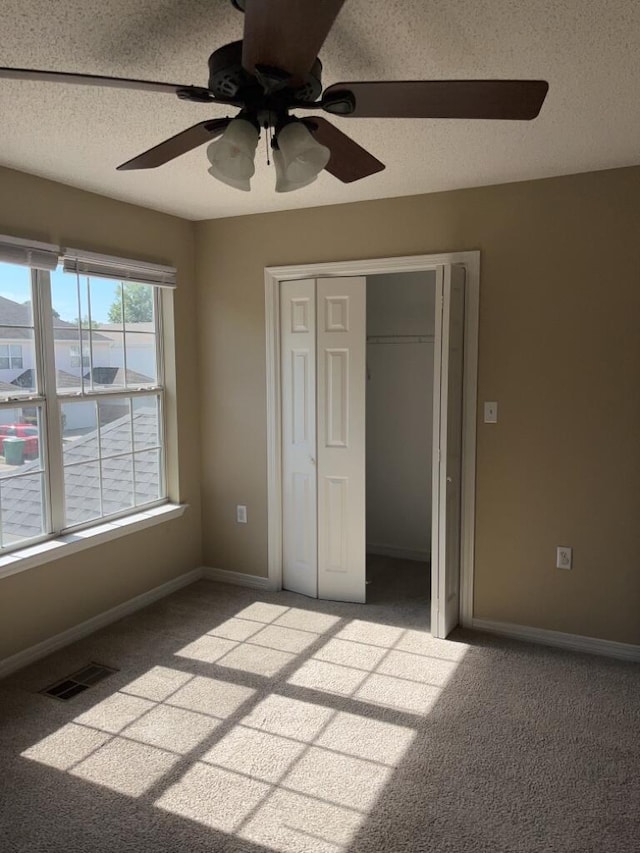 unfurnished bedroom with visible vents, baseboards, a textured ceiling, and carpet flooring