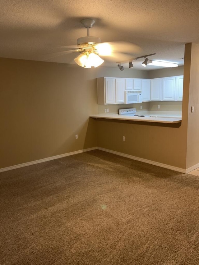 kitchen featuring white cabinets, carpet flooring, white microwave, baseboards, and stove