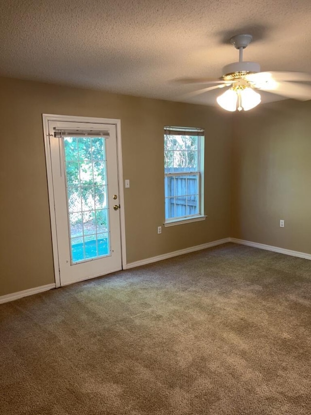 carpeted spare room with a textured ceiling, baseboards, and ceiling fan