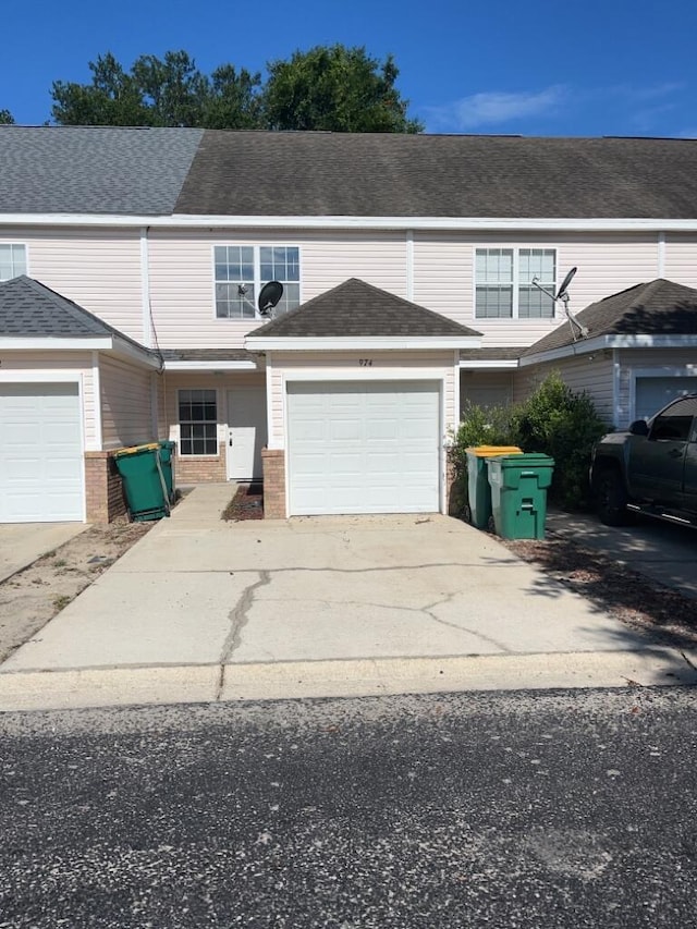 multi unit property with driveway, a garage, and roof with shingles