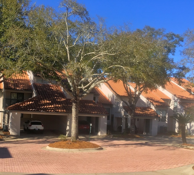 view of front of property with stucco siding, a tiled roof, an attached garage, and decorative driveway