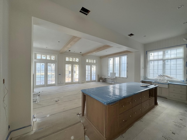 kitchen with visible vents, open floor plan, french doors, beam ceiling, and a center island