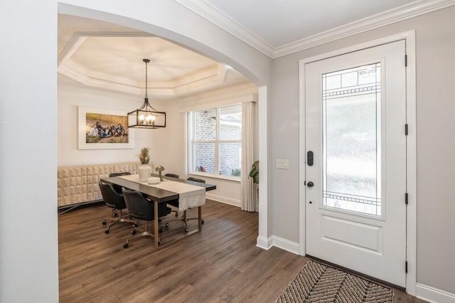 foyer entrance with dark hardwood / wood-style floors, a tray ceiling, a notable chandelier, and ornamental molding