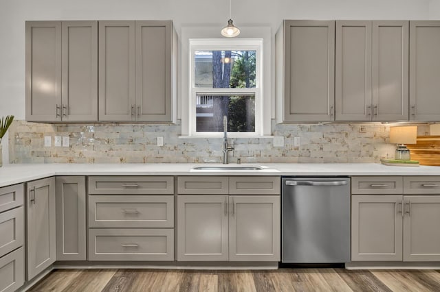 kitchen with a sink, decorative backsplash, gray cabinets, and stainless steel dishwasher