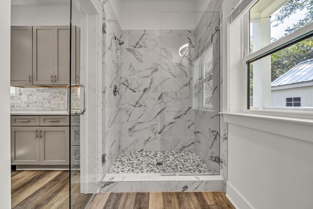 full bathroom with baseboards, vanity, a marble finish shower, and wood finished floors