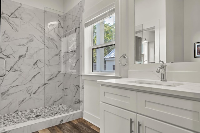 full bathroom featuring a marble finish shower, wood finished floors, and vanity