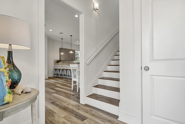 staircase with recessed lighting and wood finished floors