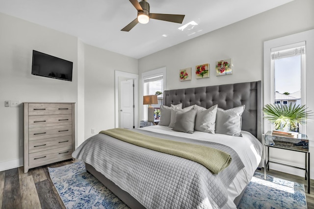 bedroom featuring baseboards, multiple windows, a ceiling fan, and wood finished floors