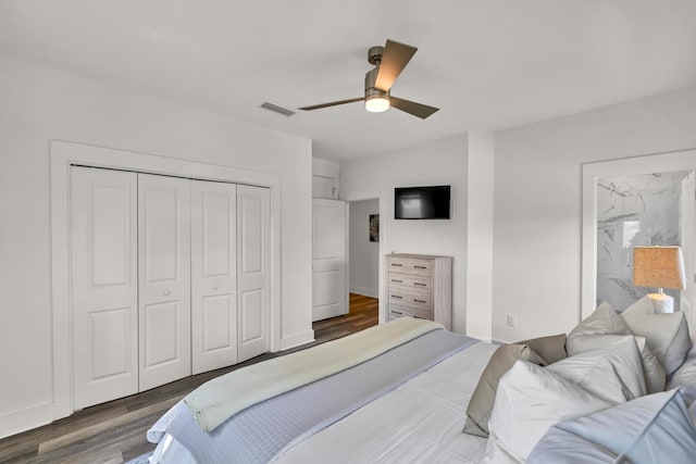 bedroom with a closet, visible vents, a ceiling fan, wood finished floors, and baseboards