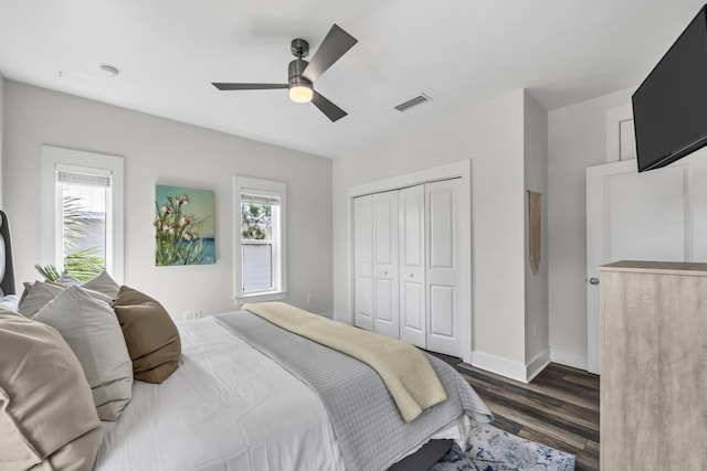 bedroom with dark wood-style floors, a closet, visible vents, a ceiling fan, and baseboards