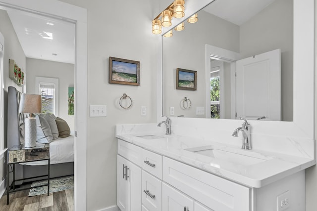 bathroom with double vanity, wood finished floors, a sink, and connected bathroom