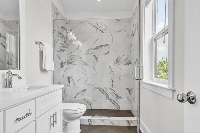 bathroom featuring toilet, a marble finish shower, and vanity