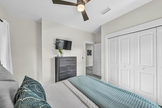 bedroom with ceiling fan, visible vents, a closet, and wood finished floors