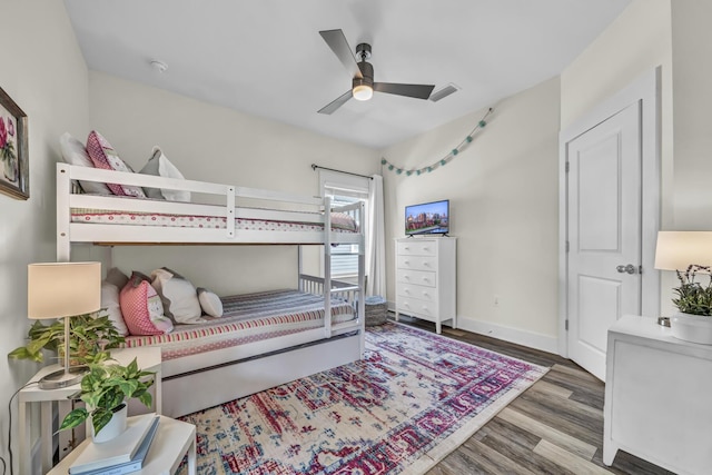 bedroom featuring baseboards, visible vents, ceiling fan, and wood finished floors