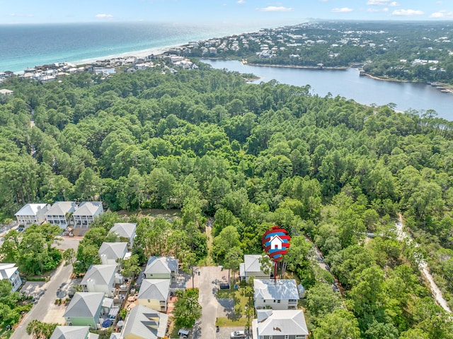 drone / aerial view featuring a forest view, a water view, and a residential view