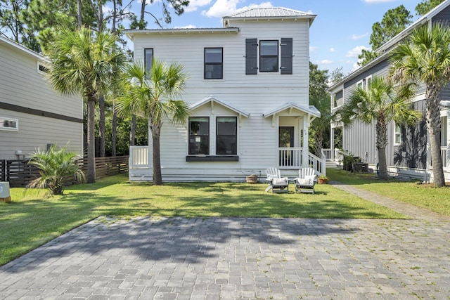 view of front of property with metal roof, fence, and a front lawn