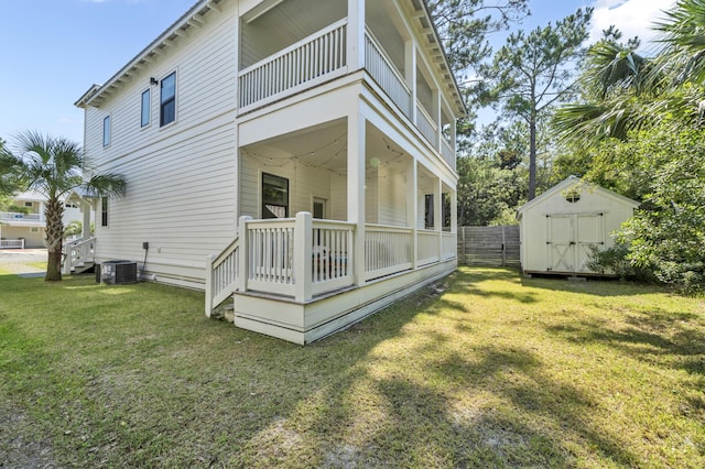 view of property exterior featuring an outbuilding, cooling unit, a balcony, a lawn, and a storage unit