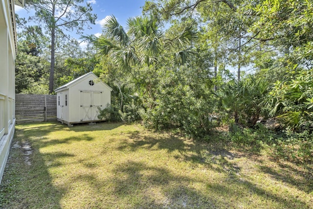 view of yard with a fenced backyard, a storage unit, and an outbuilding