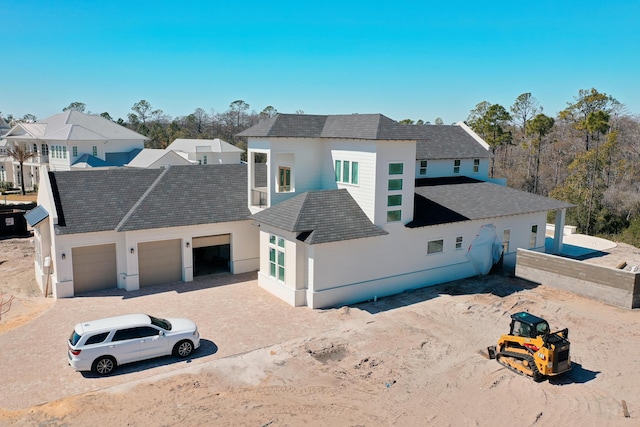 view of front facade featuring driveway, an attached garage, a residential view, and stucco siding