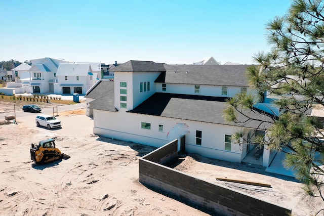 rear view of property featuring roof with shingles, fence, and a residential view