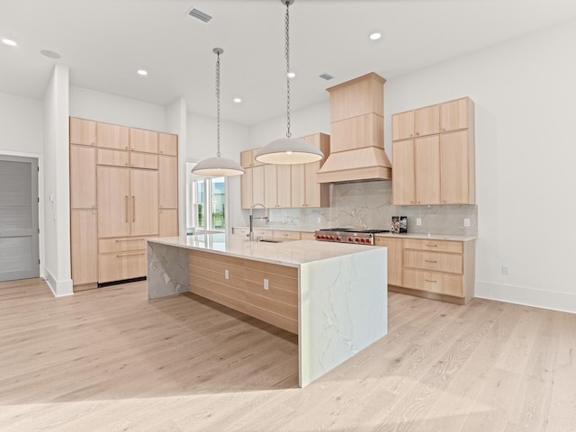 147 Quail Hollow Ct, Watersound, FL 32461 - kitchen with light brown cabinets, a sink, light wood-type flooring, backsplash, and a large island