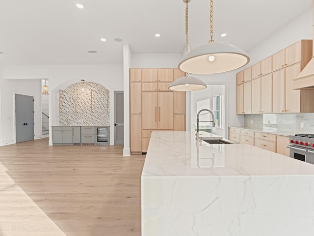 147 Quail Hollow Ct, Watersound, FL 32461 - kitchen featuring light brown cabinets, a sink, light wood-style floors, backsplash, and an island with sink