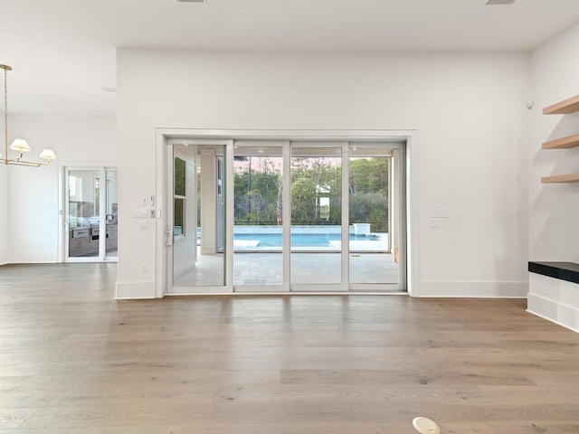 147 Quail Hollow Ct, Watersound, FL 32461 - unfurnished living room with plenty of natural light, wood finished floors, and a chandelier
