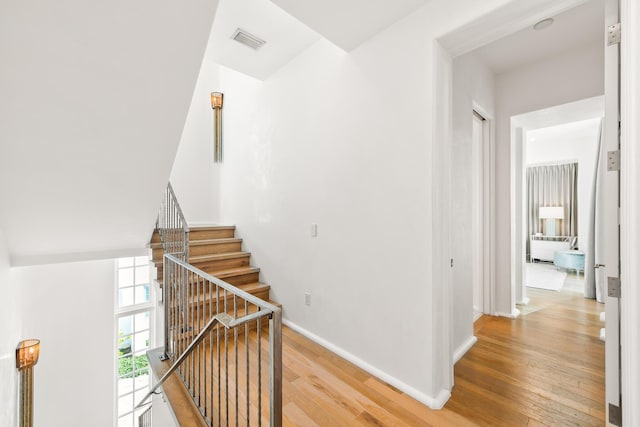 stairs with wood finished floors, visible vents, and baseboards