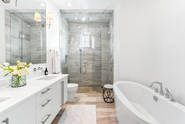 bathroom with double vanity, a stall shower, toilet, a freestanding tub, and a sink