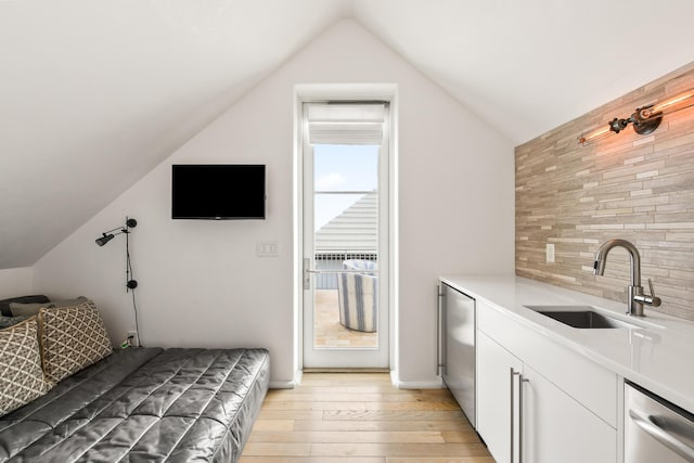 bedroom featuring vaulted ceiling, a sink, and light wood-style floors