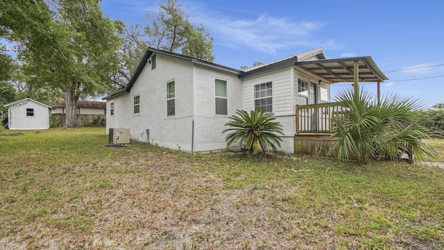 view of side of property with a storage unit, central AC unit, and a lawn