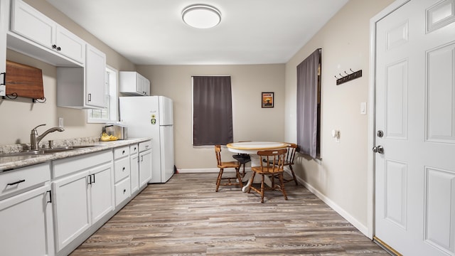 kitchen with white cabinetry, hardwood / wood-style floors, sink, and white fridge