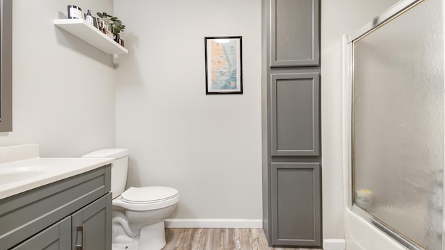 full bathroom with bath / shower combo with glass door, wood-type flooring, vanity, and toilet