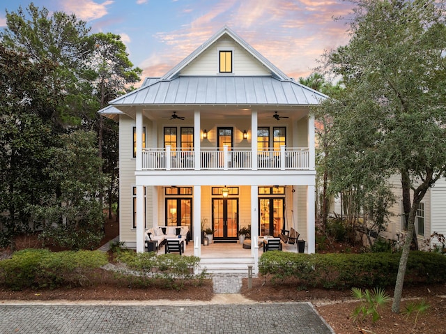 view of front facade featuring a balcony, an outdoor hangout area, a ceiling fan, french doors, and a standing seam roof