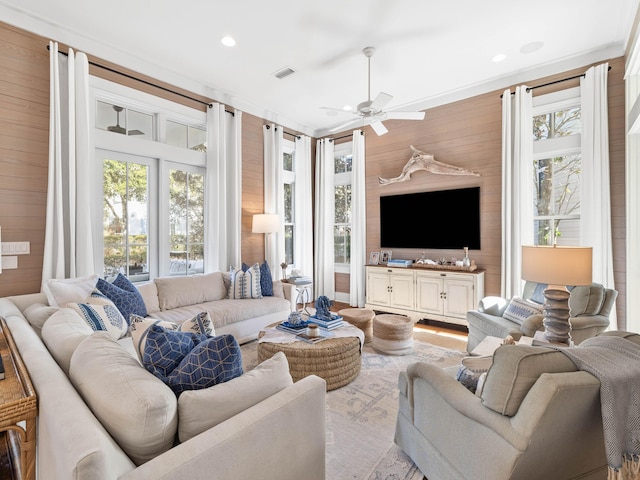 living room with wood walls, ceiling fan, visible vents, and recessed lighting