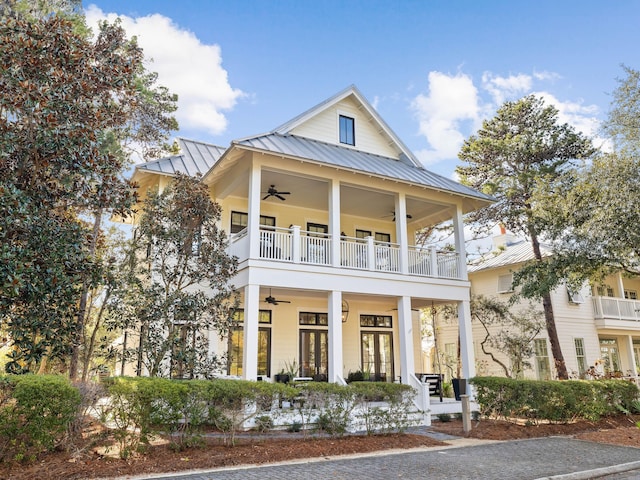 greek revival house featuring ceiling fan, metal roof, a porch, a balcony, and a standing seam roof