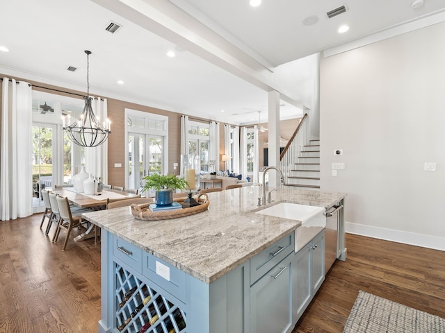 kitchen with decorative light fixtures, visible vents, dark wood-type flooring, a kitchen island with sink, and a sink