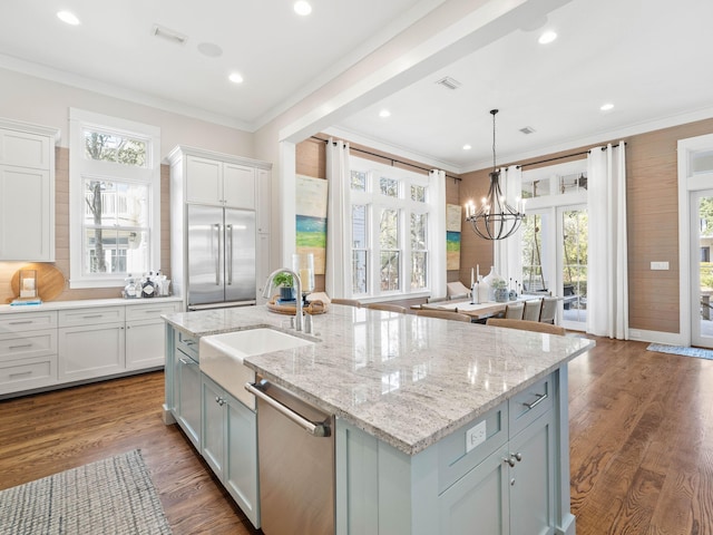 kitchen with a sink, ornamental molding, stainless steel dishwasher, an island with sink, and decorative light fixtures