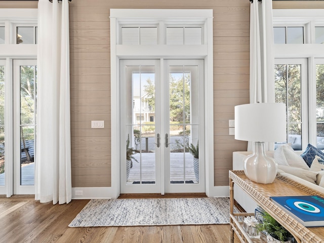 entryway with a healthy amount of sunlight, wooden walls, and wood finished floors